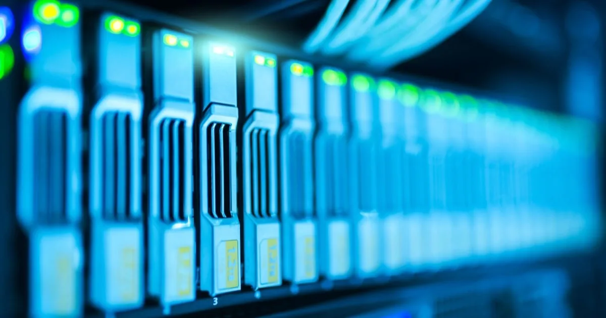 A row of illuminated computer servers receding into the distance.