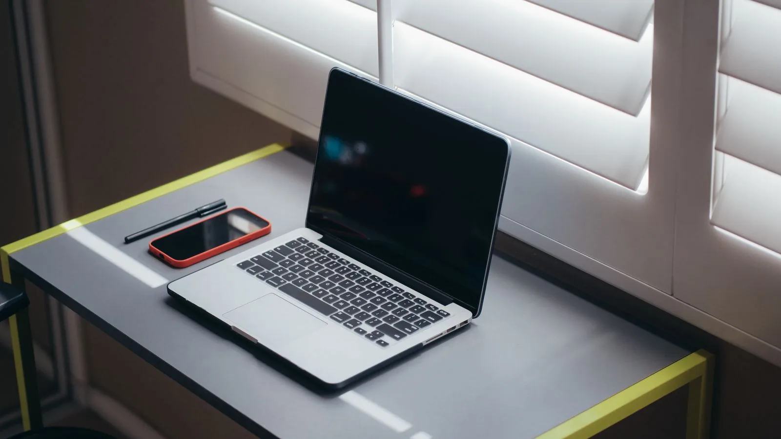 A laptop and a phone sit together on a desk.