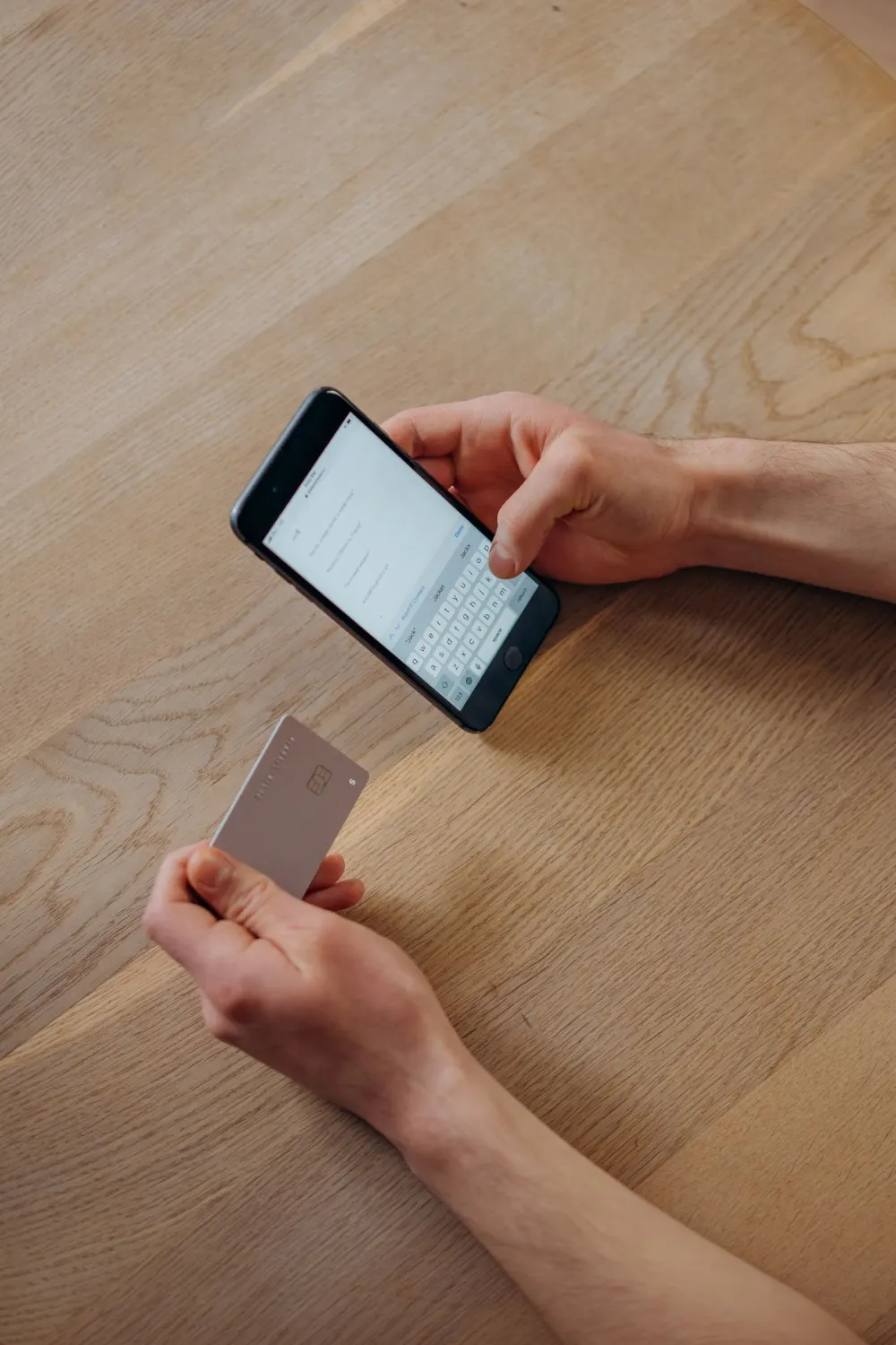 A person uses a phone while holding a bank card.