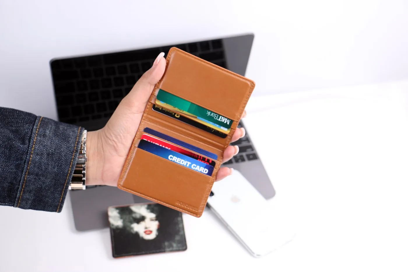 A hand holds an open wallet containing several bank cards.